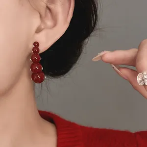 Detail view of retro red geometric drip oil bead earrings worn on the ear for a classy look