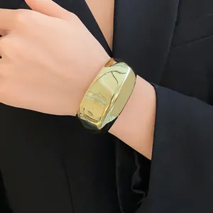 Détail d'un bracelet jonc ouvert doré, brillant et géométrique au design minimaliste.