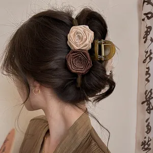 Detail of a brown Maillard-style fabric rose hair claw clip in dark hair