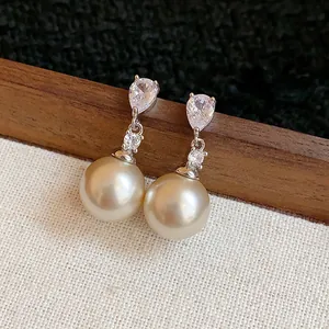 Close-up detail of elegant drop earrings featuring tear-drop zircon and champagne pearl
