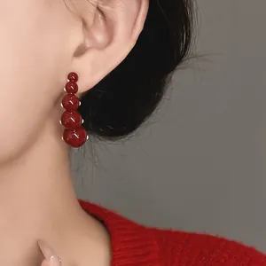 Detailed view of vintage red polka dot drop earrings with steel needles worn by an Asian model.
