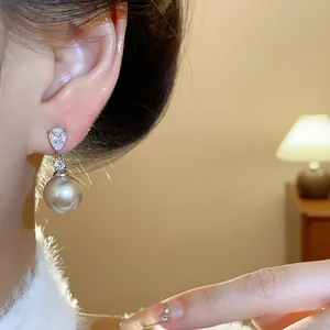 Close-up of elegant silver needle drop earrings with zircon and grey pearl