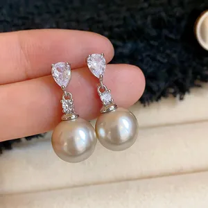 Close-up of elegant drop earrings featuring pear-cut zircon and champagne pearls