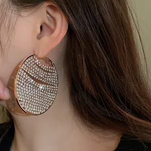 Detailed macro view of an oversized gold hoop earring encrusted with sparkling rhinestones.