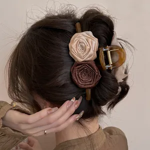 Detailed view of an acrylic hair claw clip with brown fabric roses worn in hair.