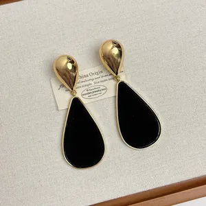 Detailed macro view of vintage gold teardrop earrings with elegant black velvet inlay