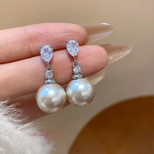 Detailed close-up view of elegant pearl drop earrings with sparkling zirconia stones.