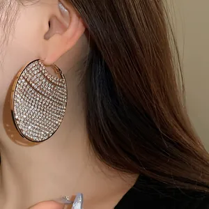 Close-up of oversized gold hoop earrings fully encrusted with sparkling zirconia stones