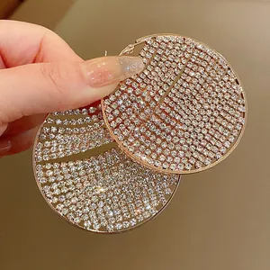 Macro detail of oversized sparkling rhinestone pave hoop earrings in rose gold finish.