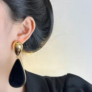 Macro view of vintage water-drop earrings featuring black velvet inlay and golden frame