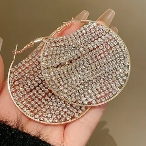 Close-up of exaggerated hoop earrings with dense zirconia stones in rose gold finish.