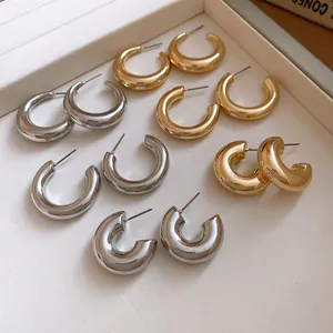 Macro view of various chunky gold and silver hoop earrings on a white display tray