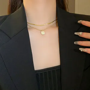 Elegant double layered gold necklace featuring hammered pendant worn with a black blazer