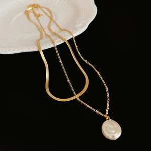 Macro detail showing textured gold double-layer chain and elegant baroque pearl pendant