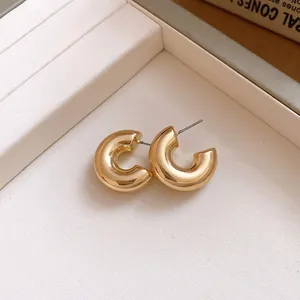 Close-up of chunky gold-colored C-shaped hoop earrings on a display tray