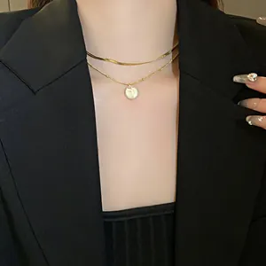 Layered gold necklace with silver nugget pendant detail worn on neck with black blazer