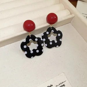 Detailansicht eleganter rot-schwarzer Blumenohrringe in einer Samtschmuckschatulle.