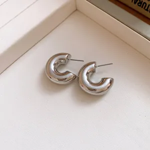 Close-up of chunky silver C-shaped hoop earrings featuring a high-polish metallic finish
