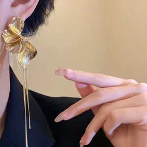 Close-up of gold flower tassel earring featuring textured petals and long metal chains