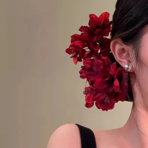 Détail d'une pince à cheveux en tissu fleur rouge portée par un mannequin pour un look élégant