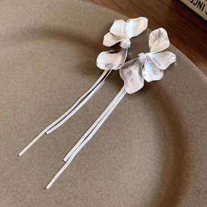 Close-up view of elegant silver flower stud earrings featuring long delicate tassel chains