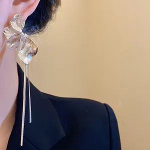 Detailed view of elegant silver flower tassel earrings on model in black blazer