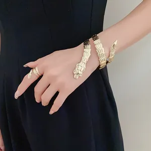 Detailed view of a golden stainless steel snake bracelet and ring set on a model