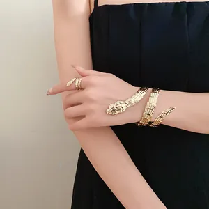 A detail view of a gold-toned snake-shaped bracelet and matching ring worn by a model