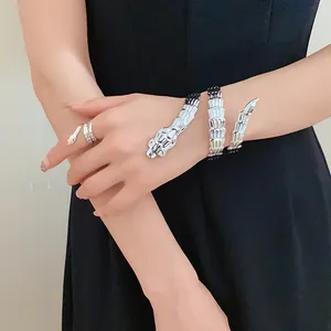 Close-up of a stylish silver snake bracelet and ring set worn on a model