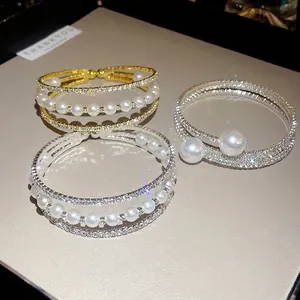 Elegant triple-layer open bangle bracelet with sparkling rhinestones and white pearls.
