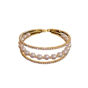 Elegant gold-toned three-layer open bangle featuring pearls and sparkling rhinestones