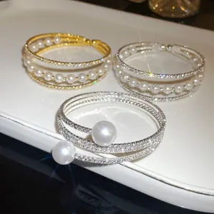 Detailed view of luxury multilayer bracelets featuring sparkling rhinestones and white pearls