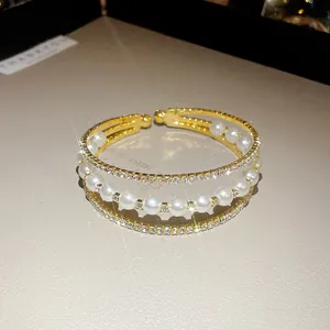 Detailed macro view of a three-layer gold bracelet with pearls and rhinestones
