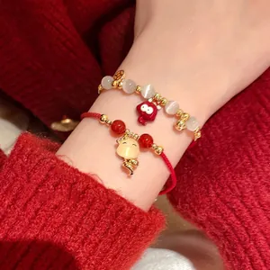Gros plan de bracelets en fil rouge et perles avec de jolis charmes de serpent mignons.