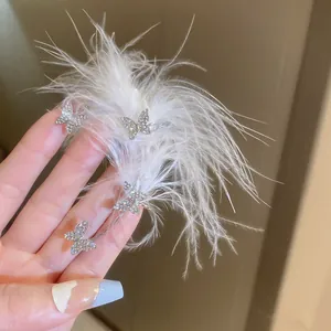 Detail of butterfly ear cuff with shimmering rhinestones and soft white feathers.