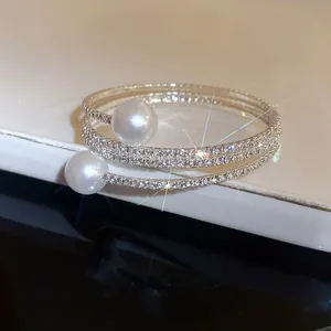 Close-up detail of a luxury triple-layer wrap bracelet featuring pearls and rhinestones