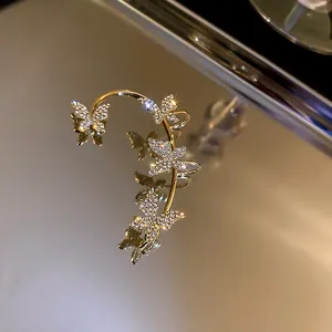 Macro detail of elegant golden butterfly ear cuff decorated with sparkling rhinestones
