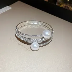Detailed macro view of a silver triple-layer rhinestone bracelet with elegant white pearl accents