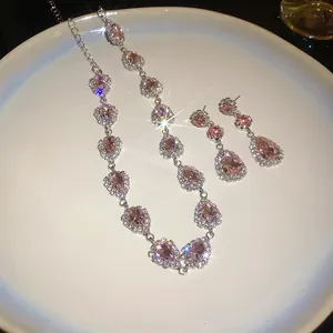 Detailed view of pink water drop rhinestone necklace and earrings on a white plate