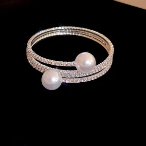 Detailed view of silver three-layer open bracelet with rhinestones and faux pearls
