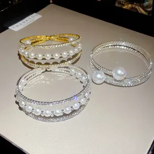 Close-up of elegant three-layer open bracelets with pearls and shimmering rhinestones