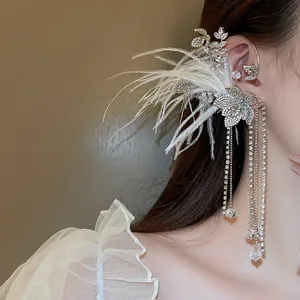 Close-up of elaborate rhinestone ear cuff with white feathers and dangling chains