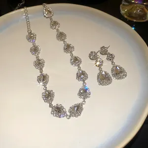 Close-up of elegant teardrop crystal jewelry set with sparkling rhinestone halo on a white plate.
