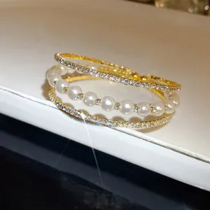 Detailed macro view of elegant three-layer gold bangle with pearls and sparkling crystals