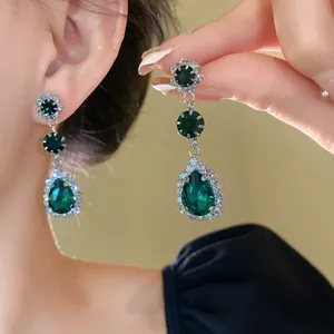 Detailed close-up of emerald green crystal teardrop drop earrings with rhinestones