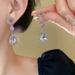 Close-up of elegant pink teardrop crystal dangling earrings worn by a model in detail view