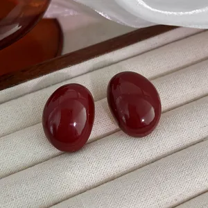 Close-up detail of elegant glossy deep red oval stud earrings inside a jewelry box