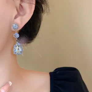 Close-up of elegant silver teardrop dangling earrings with crystals worn by a model