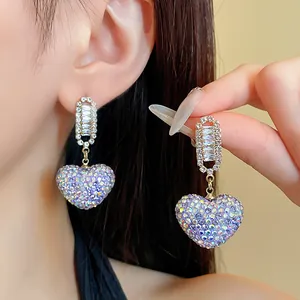 Détail de boucles d'oreilles pendantes en cœur avec strass scintillants