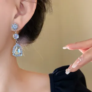 Elegant close-up of sparkling teardrop drop earrings featuring a brilliant silver halo setting
